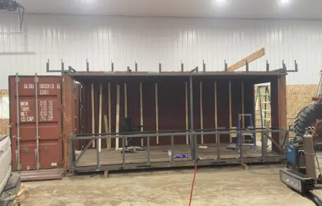 An interior view of a shipping container being converted into a structure, with wooden framing.